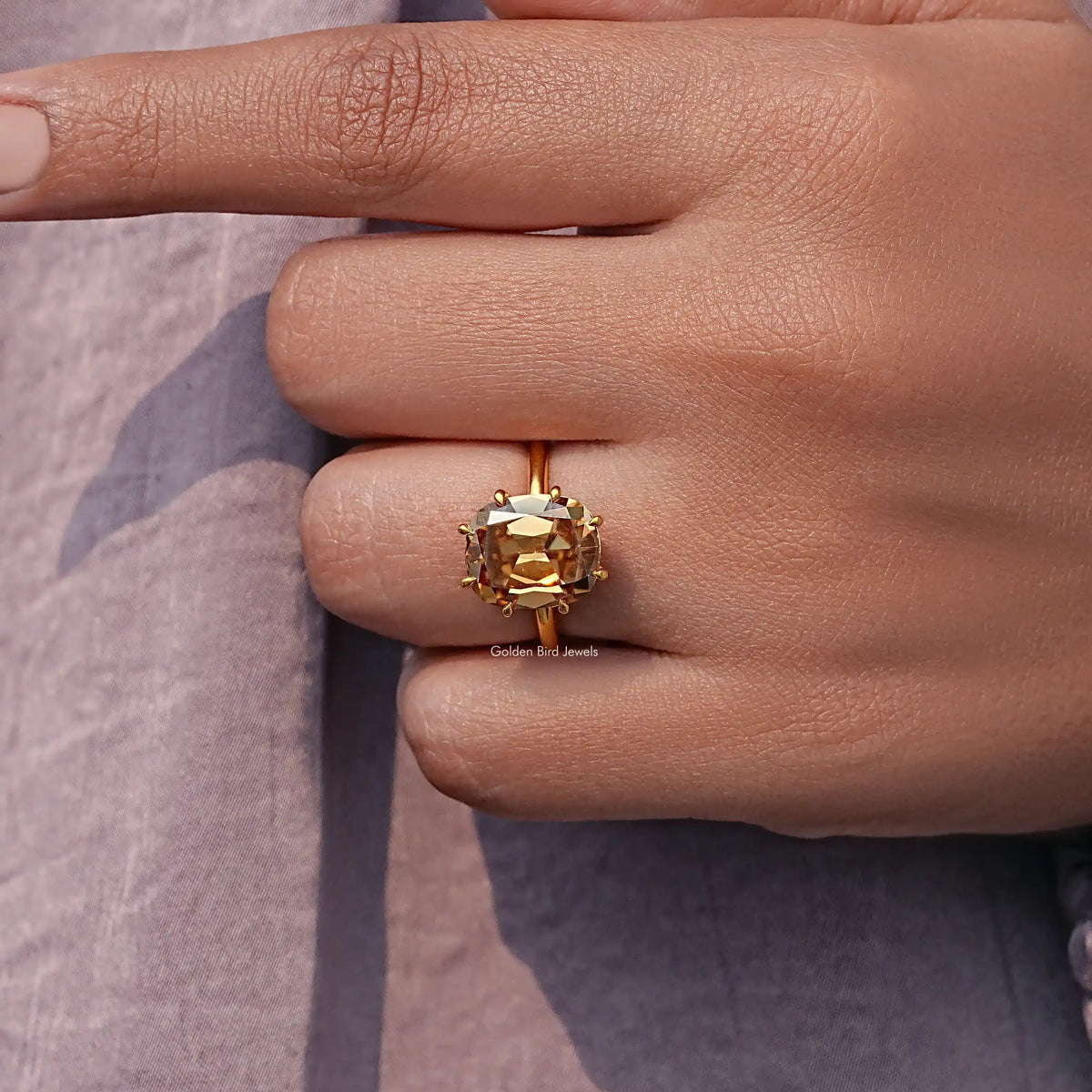 Champagne cushion-cut moissanite stone with gold prongs in close-up