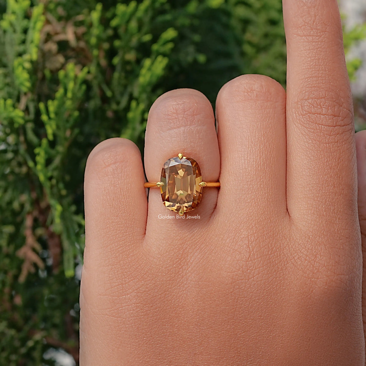 Solitaire cushion-cut moissanite ring with golden center stone on a gold band
