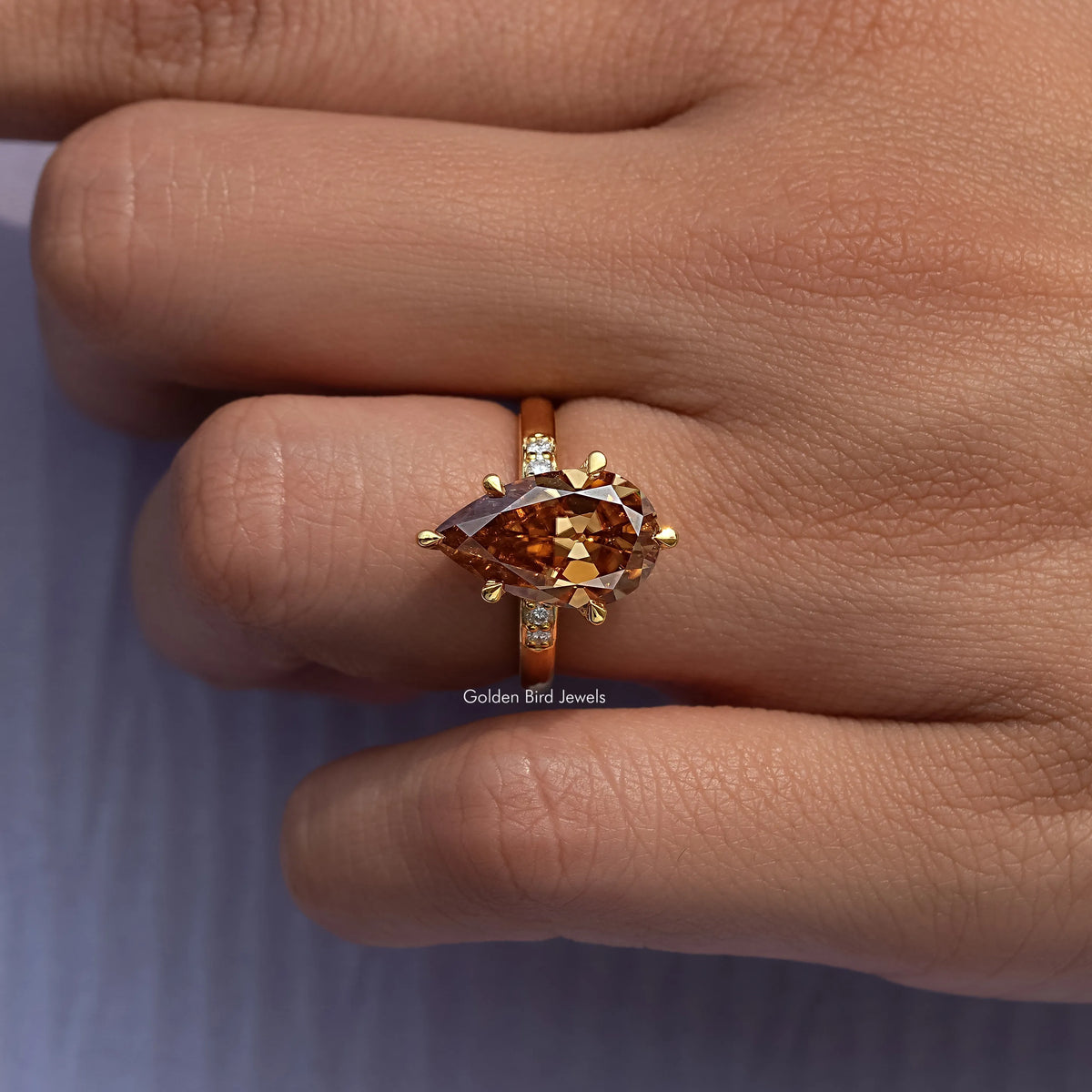 Gold ring with pear-cut amber center stone and small square side stones