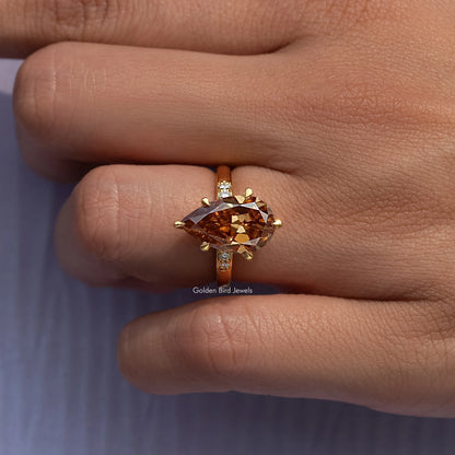 Gold ring with pear-cut amber center stone and small square side stones