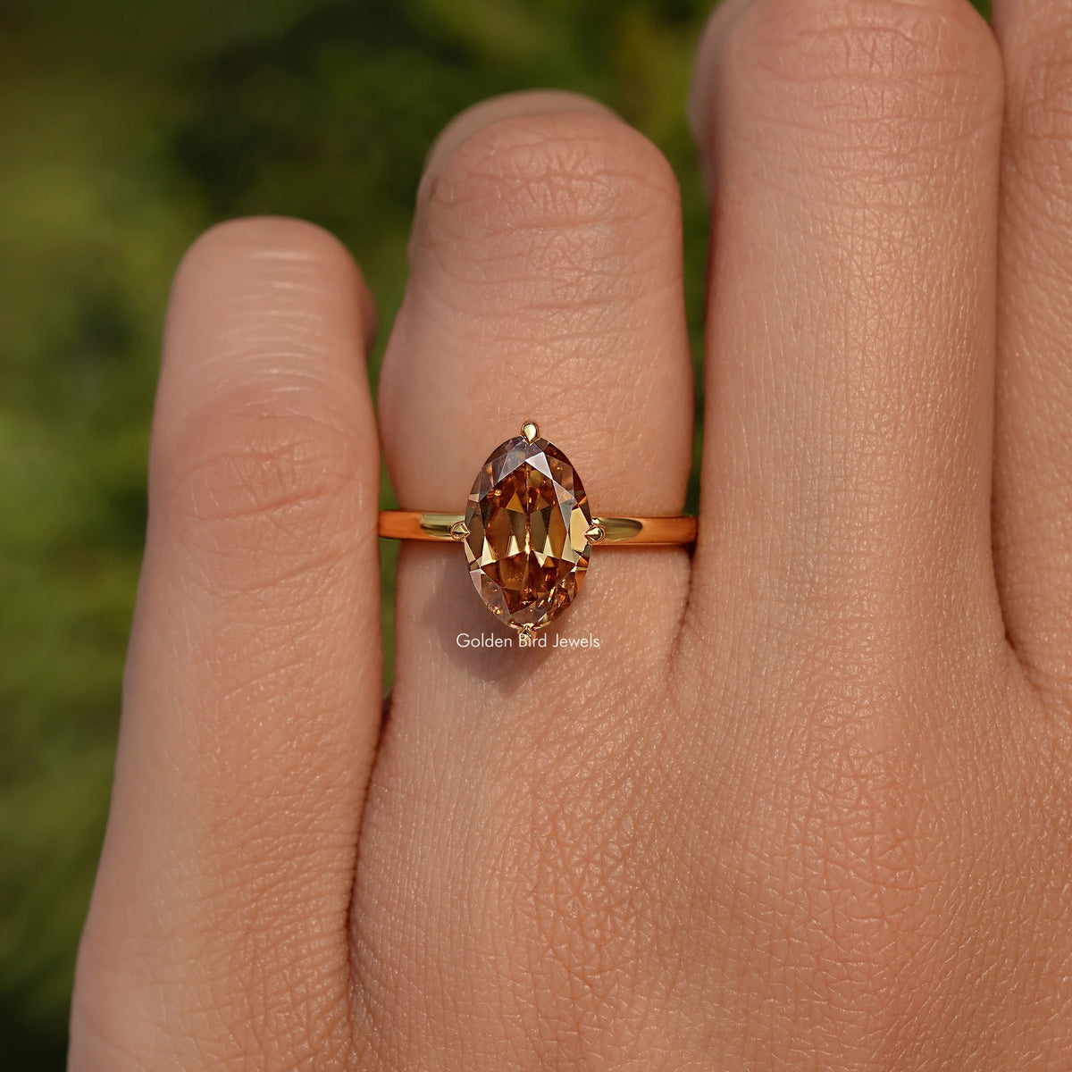 Oval champagne moissanite solitaire ring on finger, gold band with thin shoulders