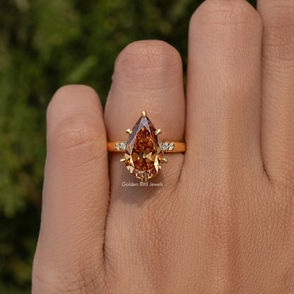 Gold ring with large pear-cut cognac center stone and tiny square side stones