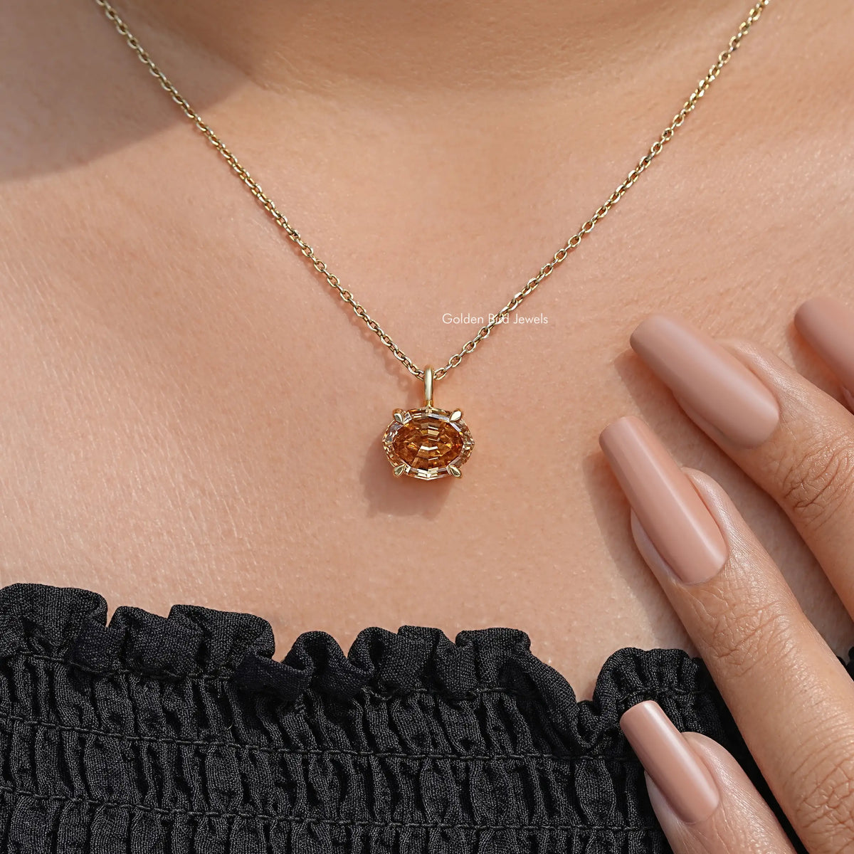 Champagne oval moissanite pendant on gold chain, close-up with fingers