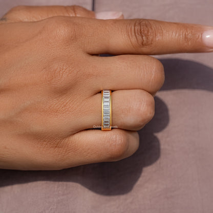 Yellow gold baguette-cut moissanite channel-set wedding band, close-up on hand