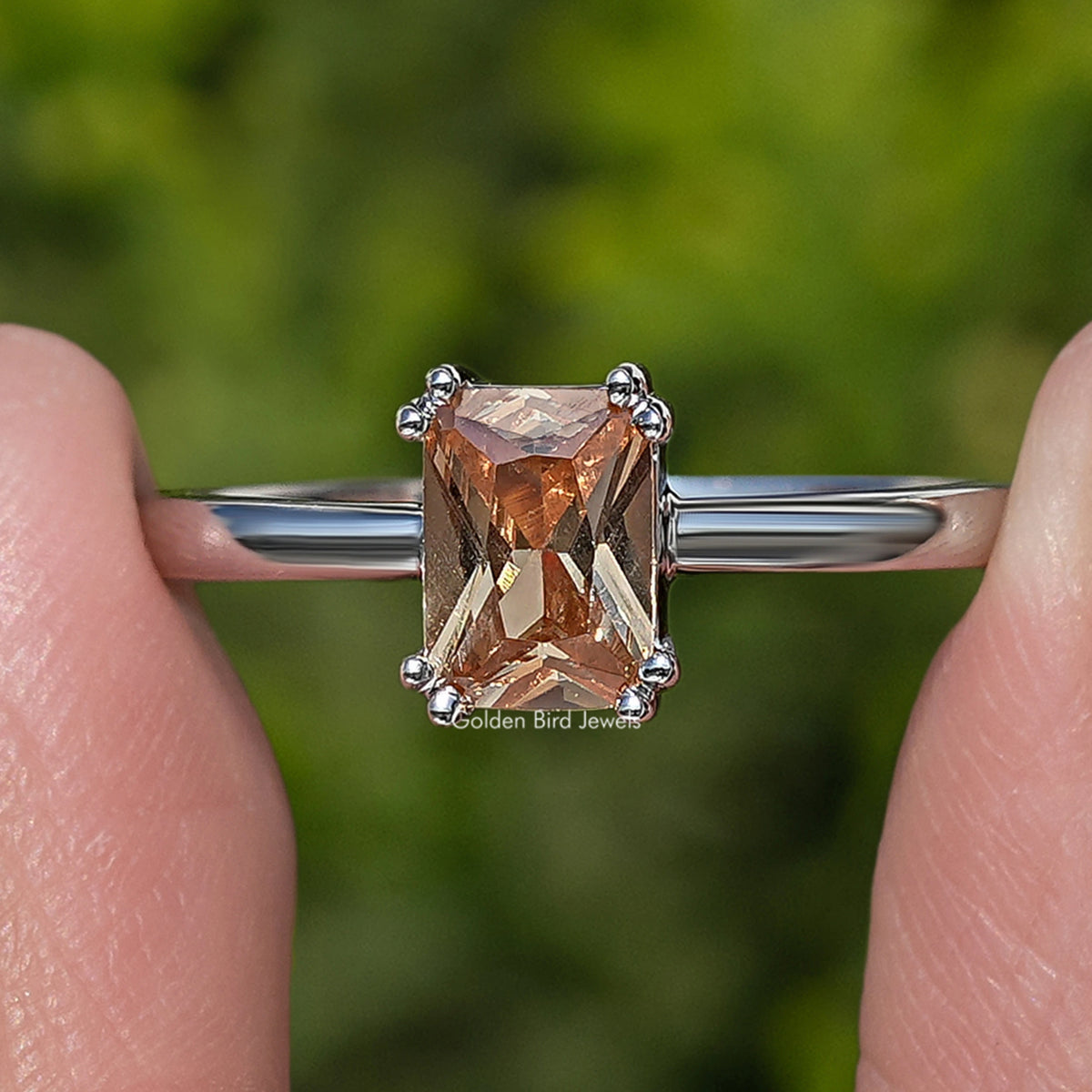 Silver ring with orange faceted gemstone framed by four corner prongs