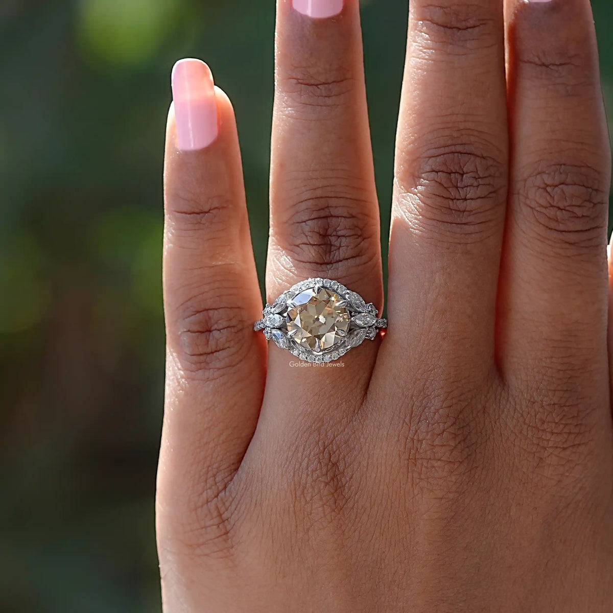 Silver halo cluster ring with round champagne center stone on hand close-up