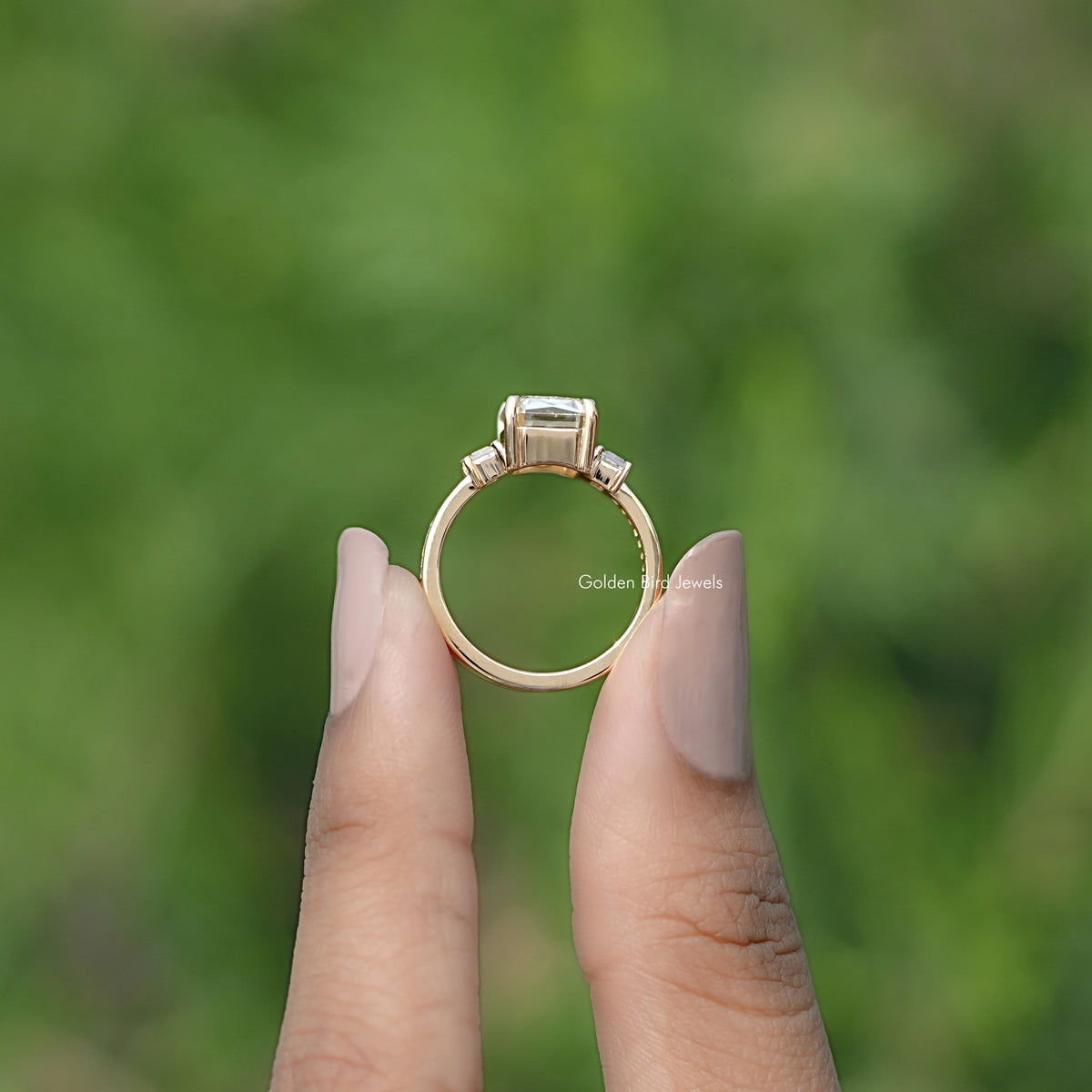 Three-stone ring with large square-cut center stone and two baguette side stones, gold-tone