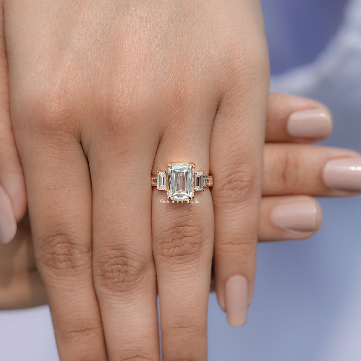 Three-stone moissanite-style ring on hand, square center stone with two side baguette stones