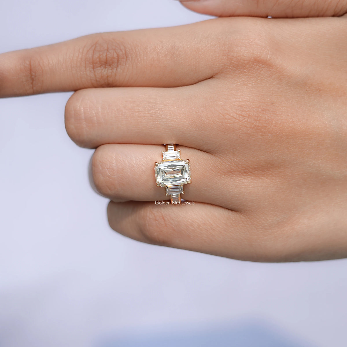 Gold-tone three-stone ring with square-cut center stone and baguette side stones