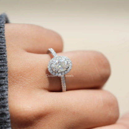 Oval halo moissanite ring with pavé band, shown on a finger