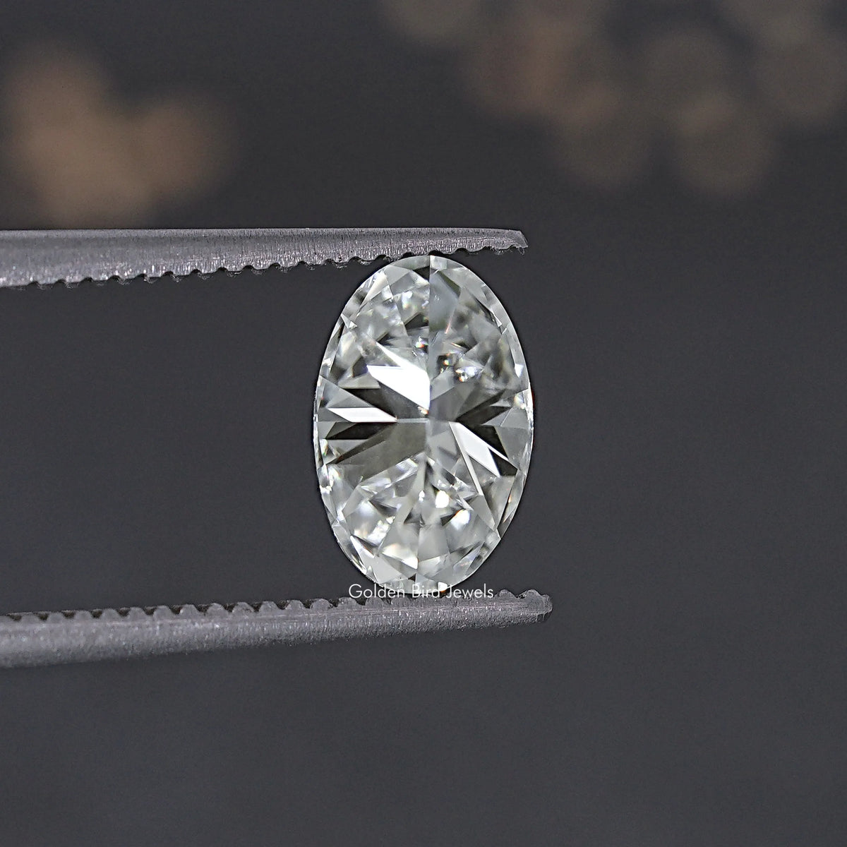 Oval crushed ice moissanite gemstone held in tweezers, bright reflective facets