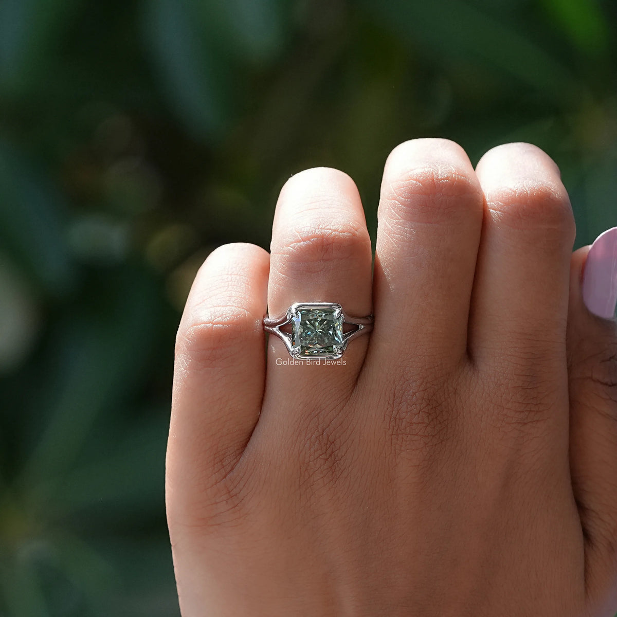 Silver engagement ring with emerald-cut moissanite center stone on hand