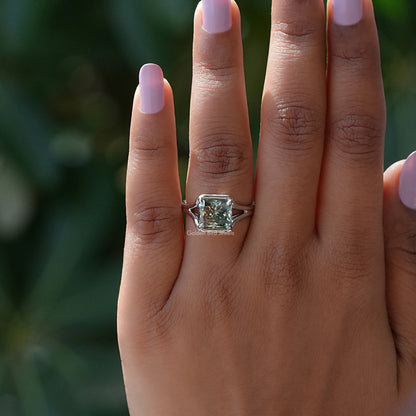 Emerald-cut moissanite engagement ring with silver prong setting on fingertip
