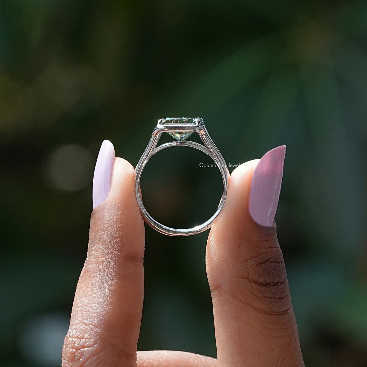 Silver ring band with open-back setting holding an emerald-cut moissanite
