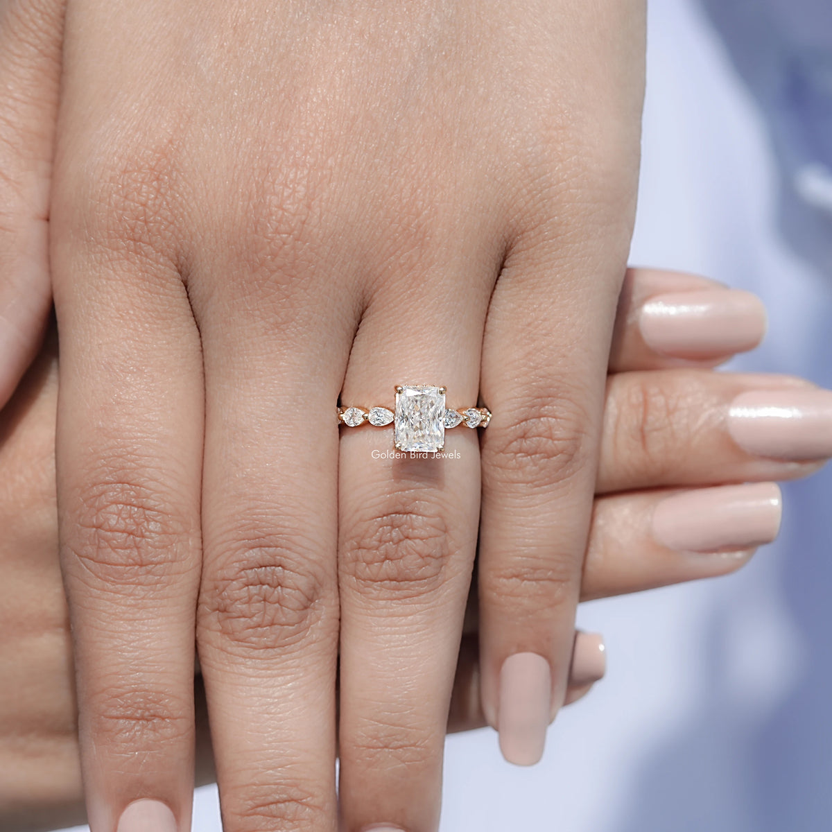 Silver-tone radiant-cut halo ring on finger with small round side stones.