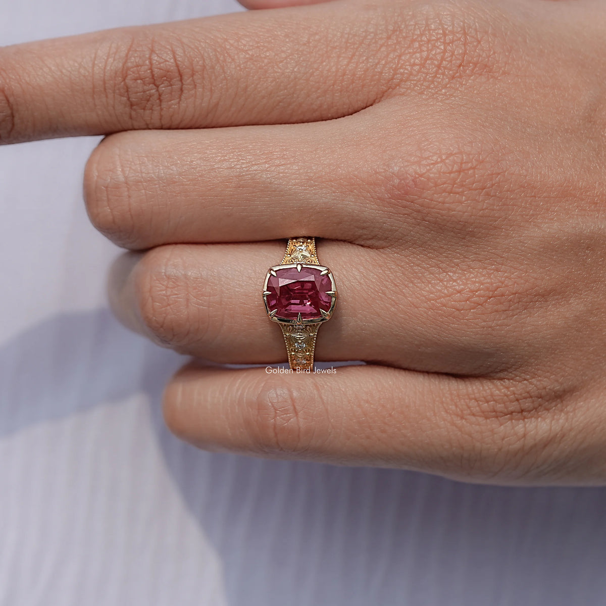 Cushion-cut gemstone ring with a yellow gold band and pink center stone