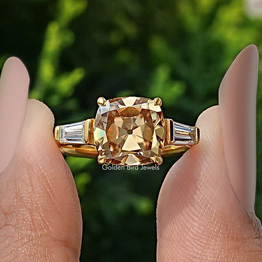 Gold three-stone engagement ring with large cushion center stone and baguette side stones