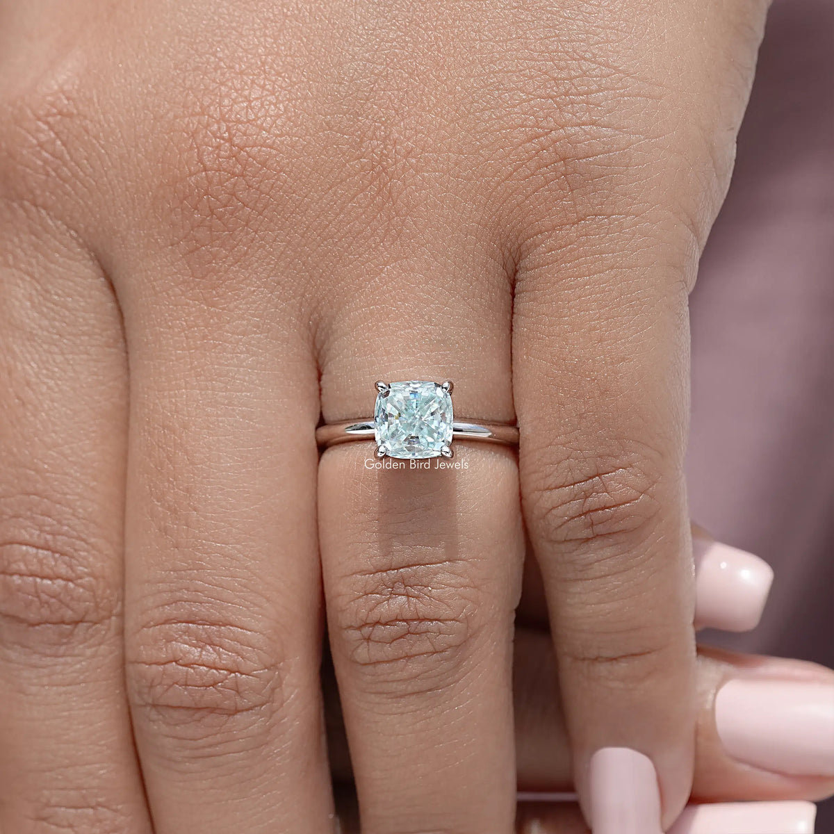 Sterling silver cushion-cut moissanite solitaire ring on fingers, close-up