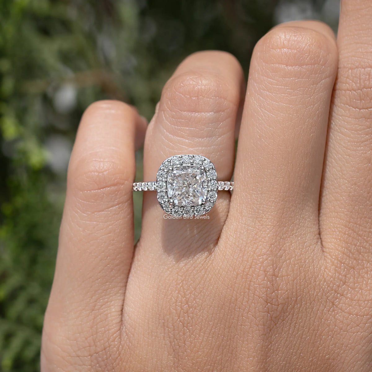 Silver-tone cushion-cut halo ring with sparkling side band, close-up on hand
