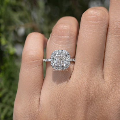Silver-tone cushion-cut halo ring with sparkling side band, close-up on hand
