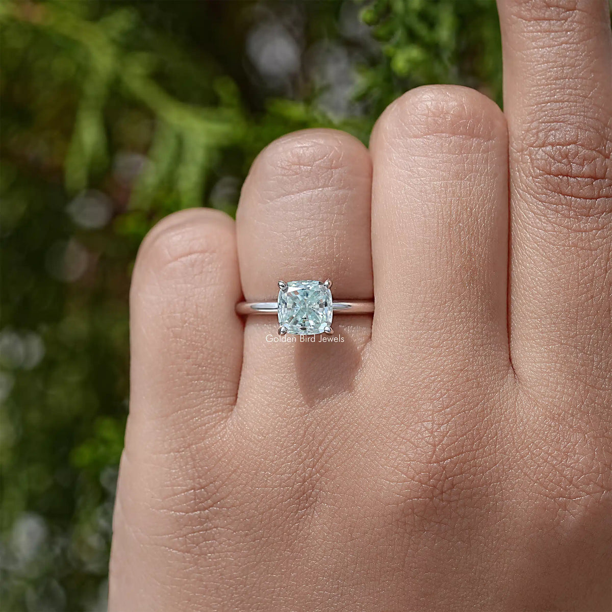Sterling silver cushion-cut moissanite solitaire ring with hidden halo on finger