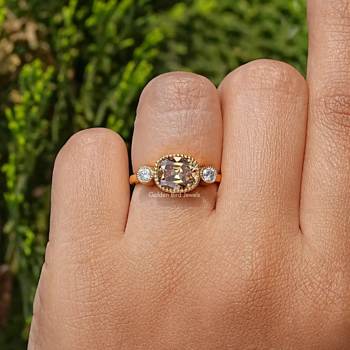 Yellow gold three-stone ring with cushion-cut center stone and round side stones