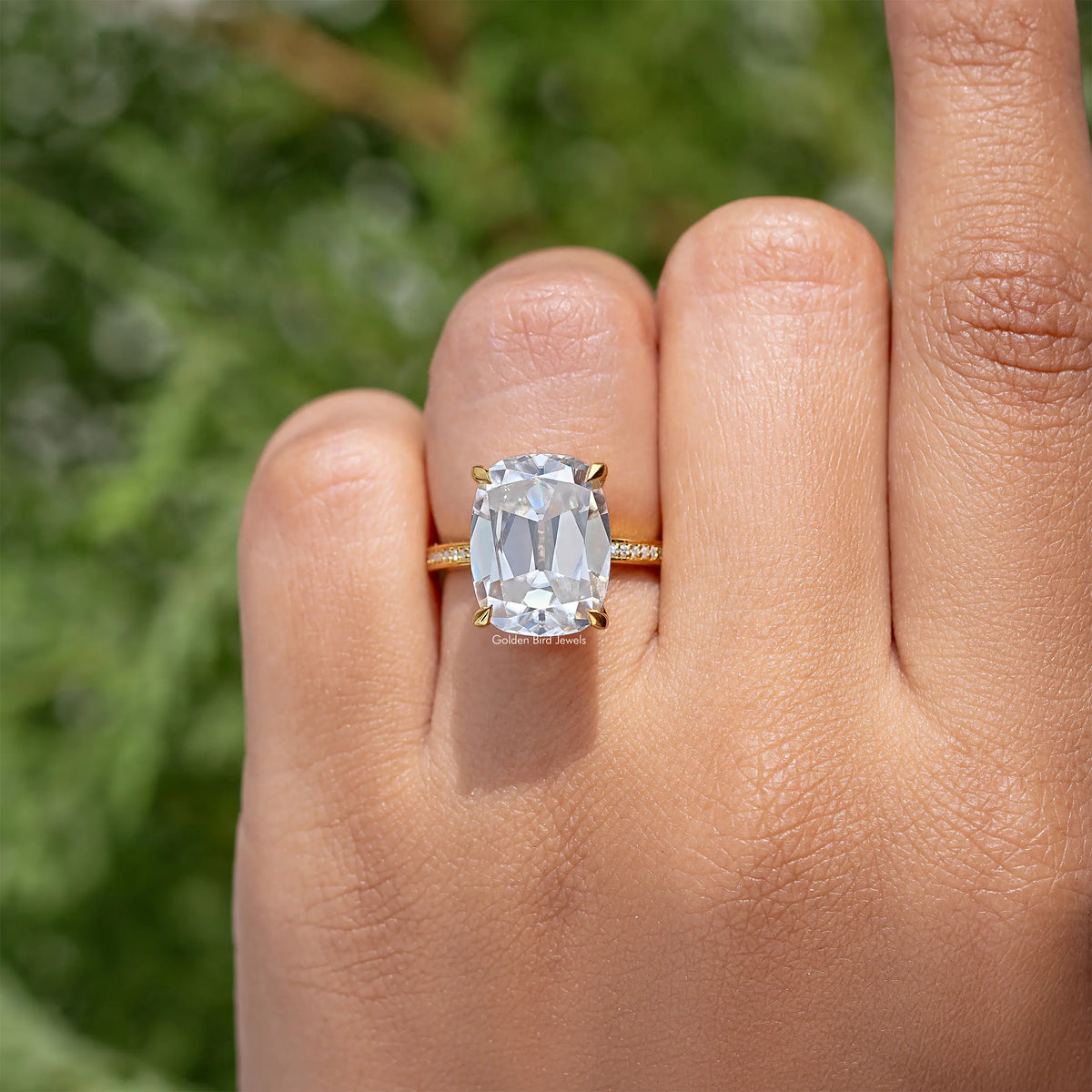 Gold cushion-cut engagement ring on finger with clear center stone and slim band