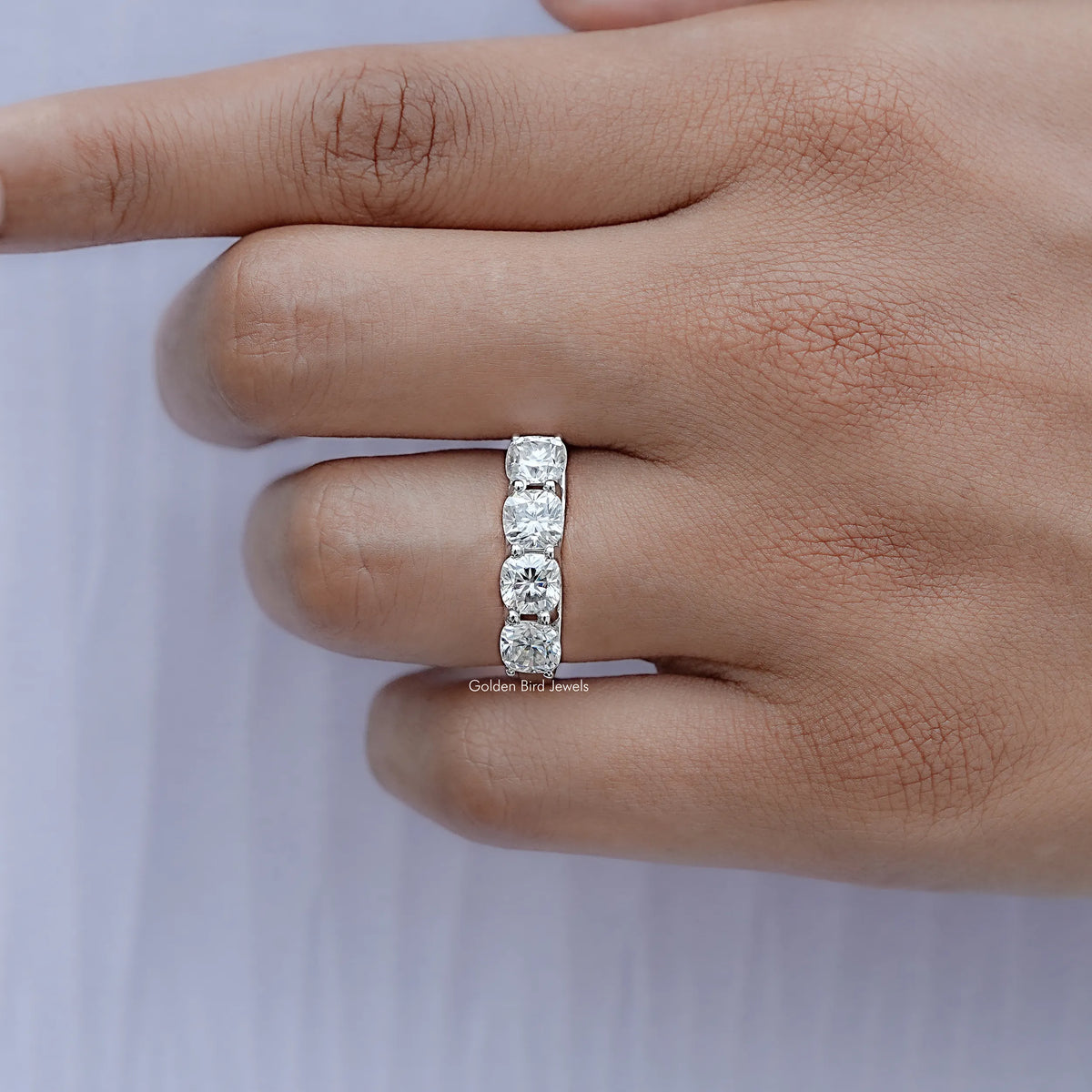 Silver cushion-cut moissanite eternity band on finger, side view with prong-set stones