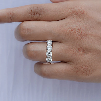Silver cushion-cut moissanite eternity band on finger, side view with prong-set stones