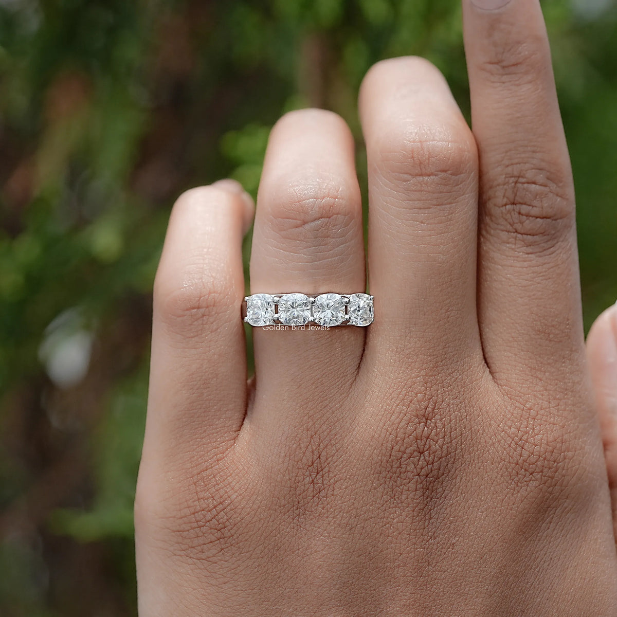 Silver cushion-cut moissanite eternity band on hand with multiple bezel-set stones