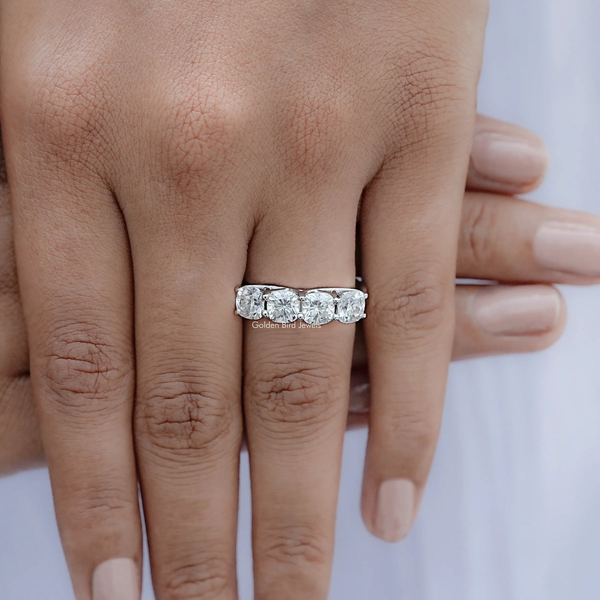 Cushion-cut moissanite eternity band on finger with five prong-set stones