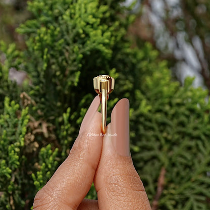 Gold-tone ring profile with prongs and detailed top bezel on fingertip close-up.