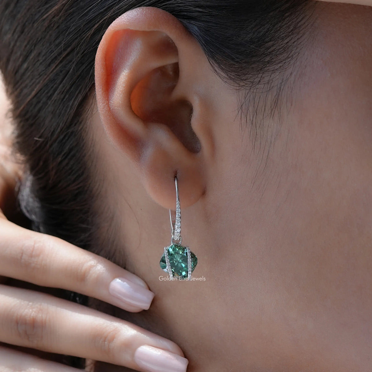 Sterling silver dangle earrings with emerald-green cushion-cut moissanite on ear