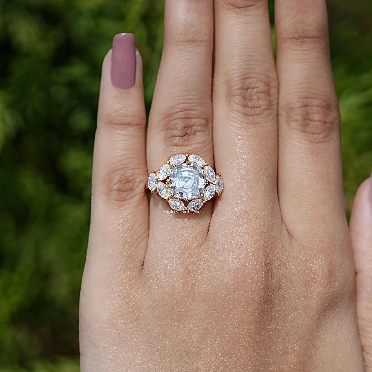 14K yellow gold halo engagement ring on palm with step-cut center moissanite
