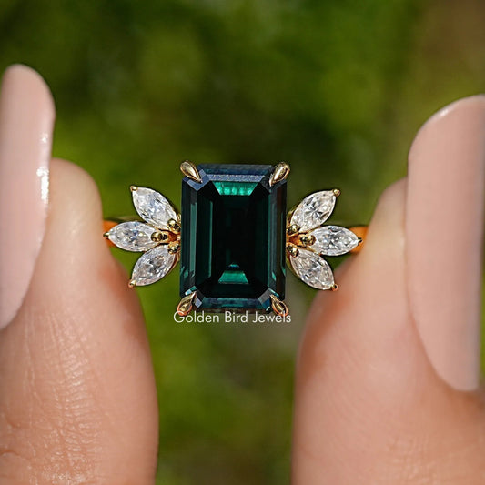 Gold engagement ring with dark green emerald-cut center and marquise side stones