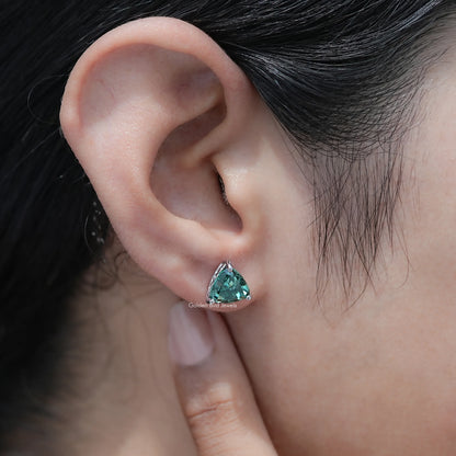 Trillion-cut dark green moissanite stud earrings on the ear, side profile