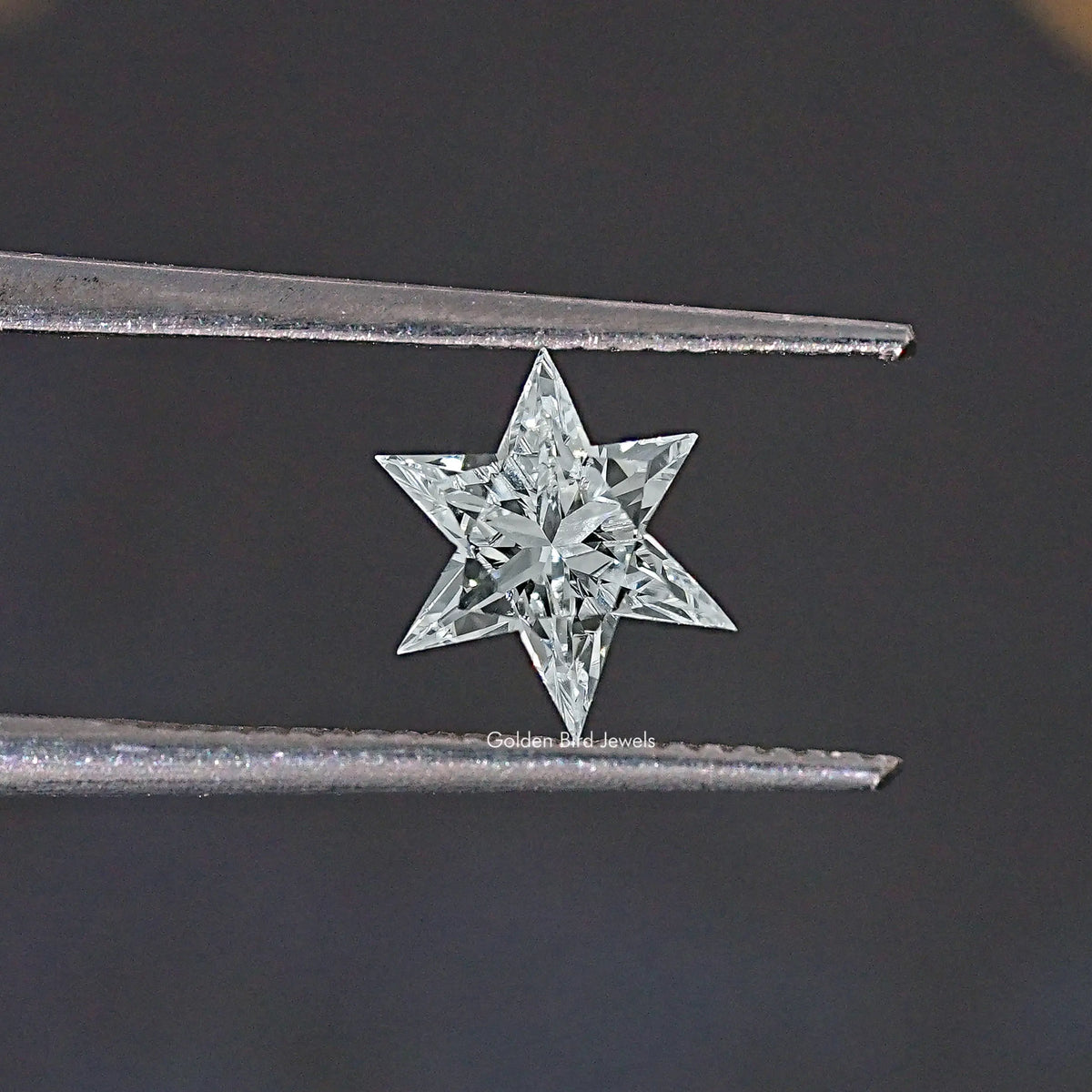 Star-cut loose lab-grown diamond held between metal prongs