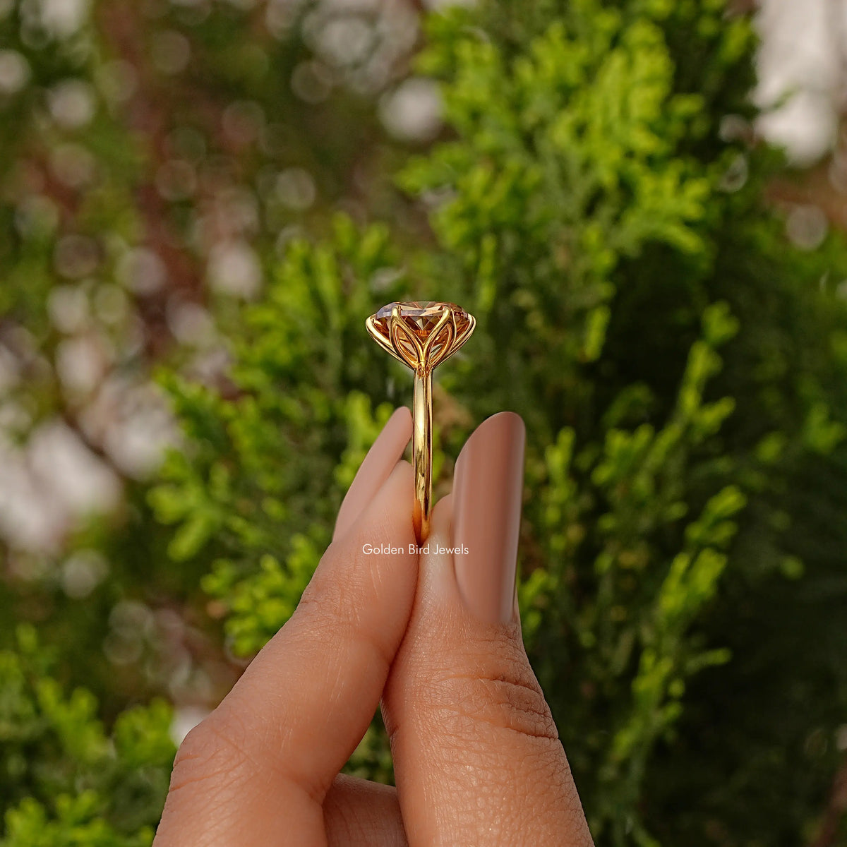Gold tone ring shown from the side: cushion-cut solitaire stone in prongs