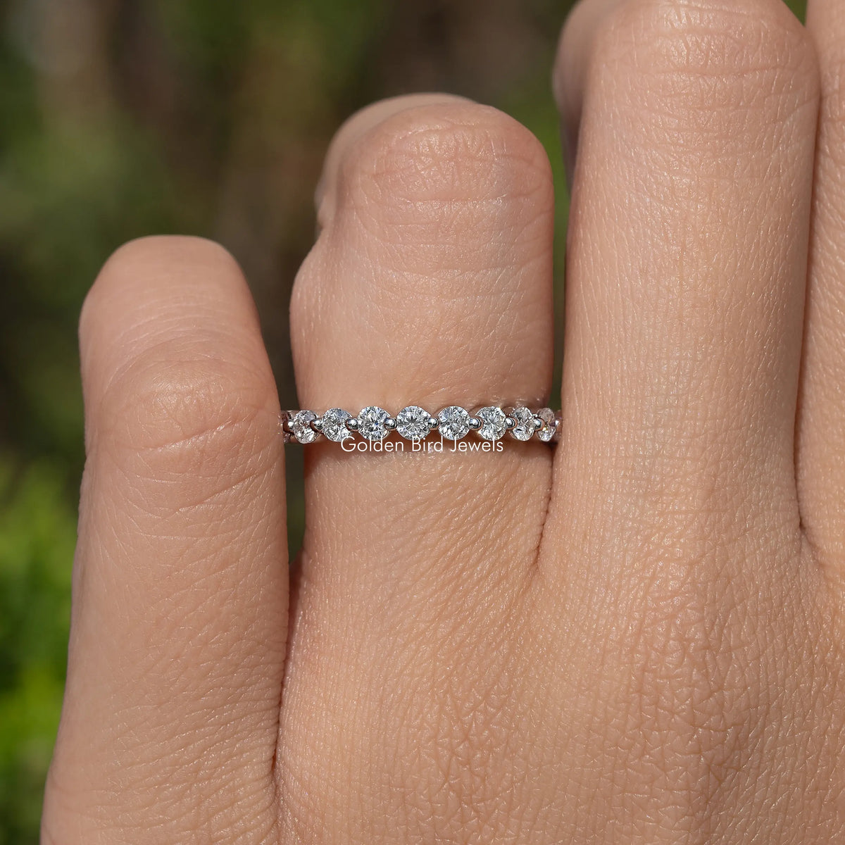 Silver-tone half eternity band with round moissanite stones on finger