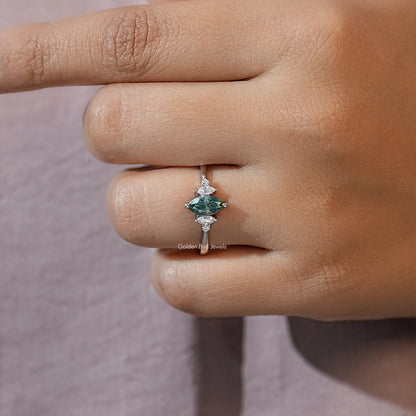 Three-stone engagement ring close-up, green marquise center with two smaller side stones