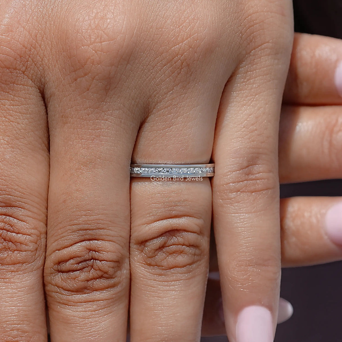 Silver-tone moissanite eternity band with round stones, front view on two fingers