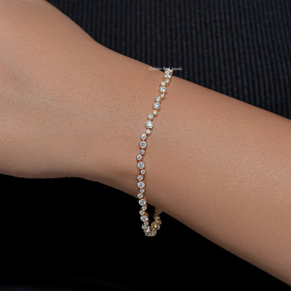 Gold-tone tennis bracelet with round bezel-set lab diamonds, wrist close-up