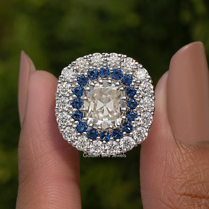Double halo cushion moissanite ring with blue inner stones and prong-set center