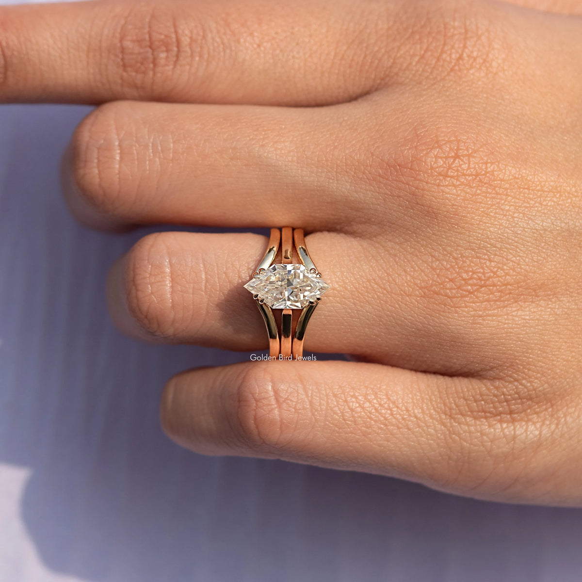 Gold tone engagement ring with large center stone and split band on finger