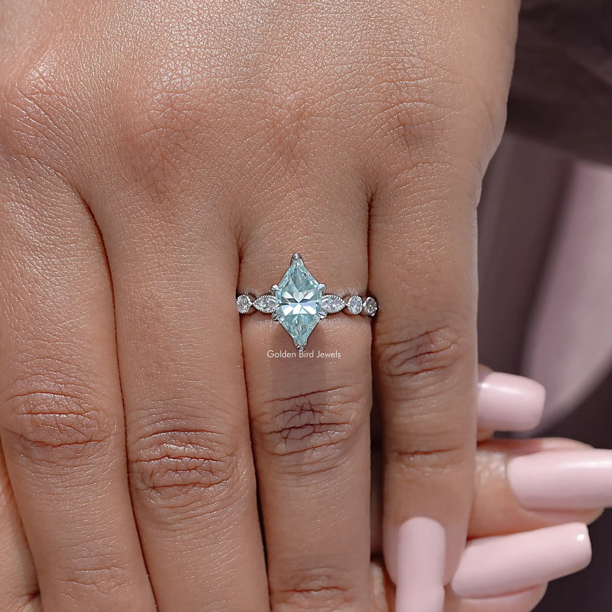 Sterling silver moissanite engagement ring on hand with blue marquise center and small side stones