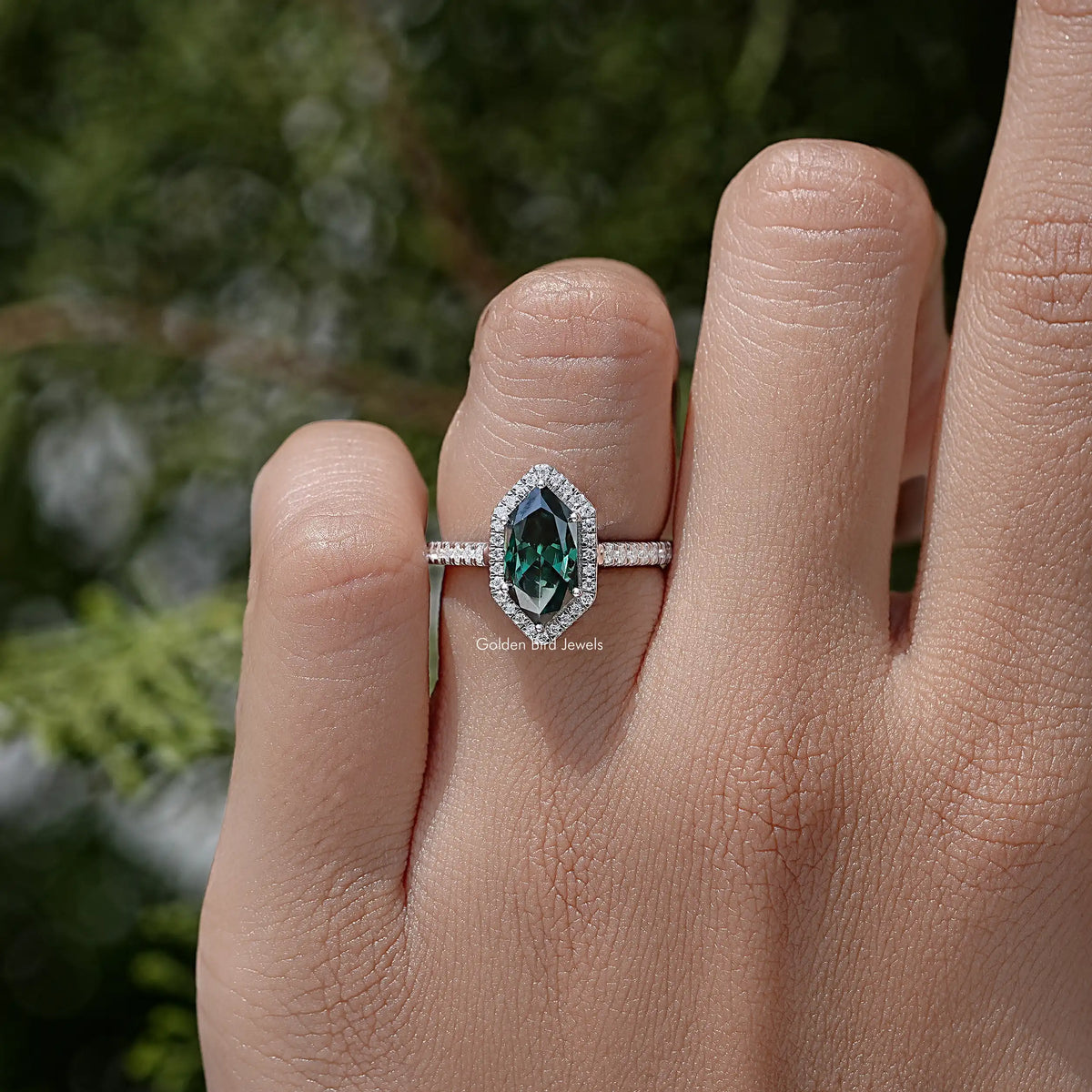 Sterling silver marquise halo accent ring with green center stone on finger