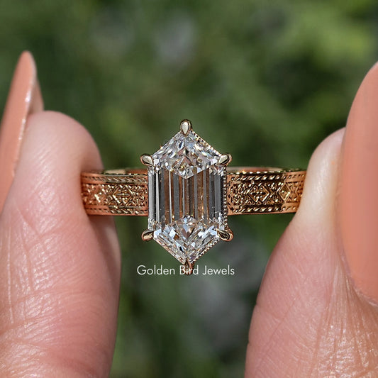 Marquise-style solitaire diamond ring with ornate gold-toned band and prong-set center stone