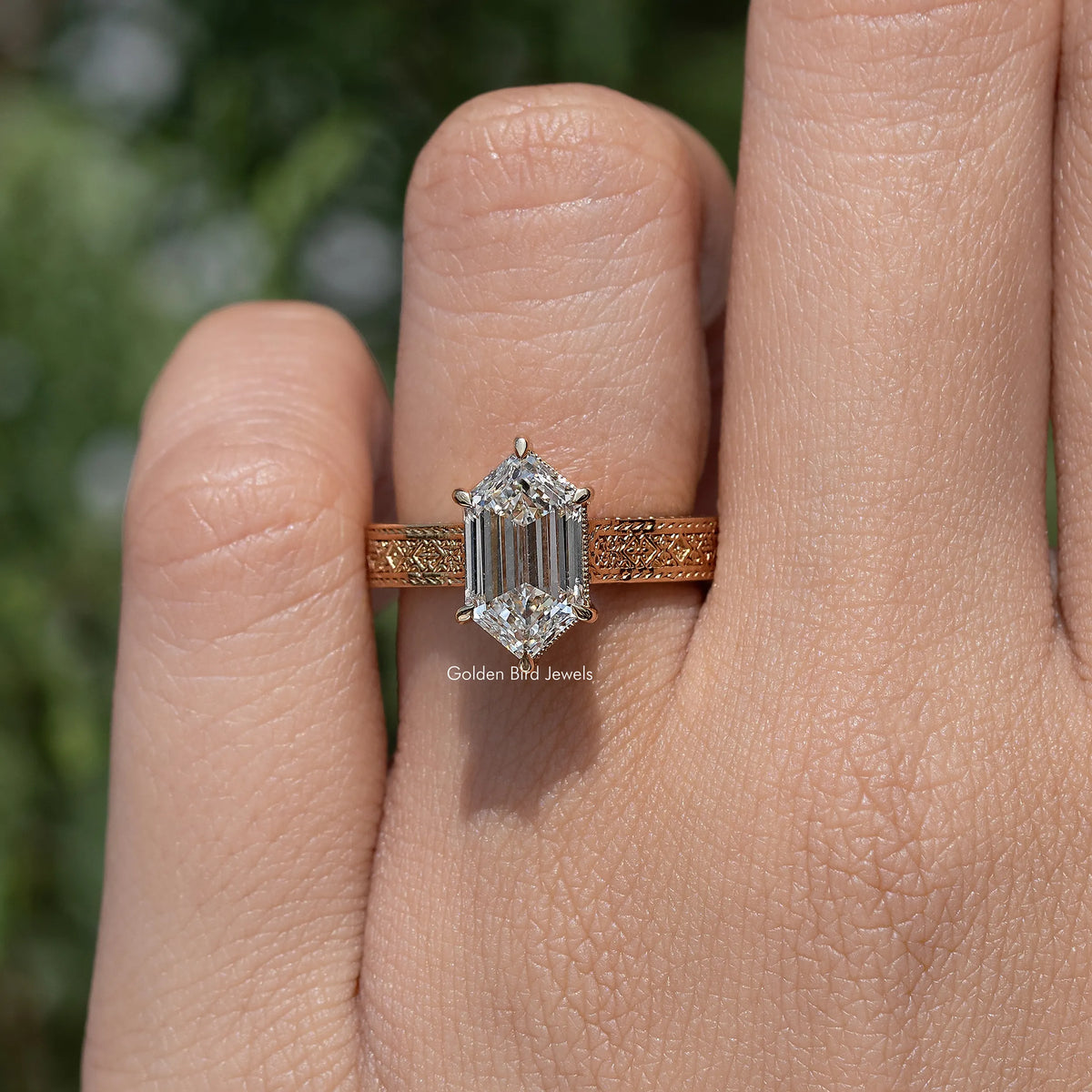 Gold-toned marquise-style solitaire engagement ring on finger with prong-set center stone
