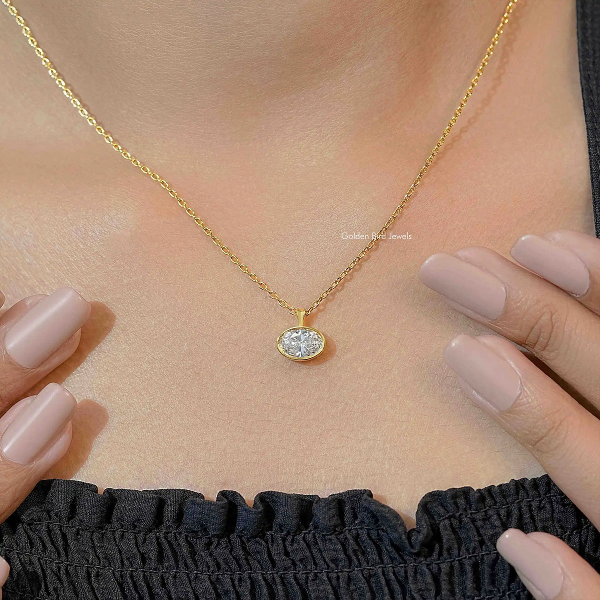 Gold-tone oval lab diamond solitaire pendant necklace worn with hands