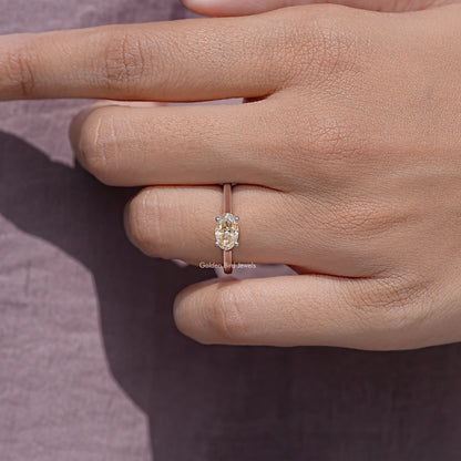 Oval cut moissanite solitaire ring with four prongs on finger.